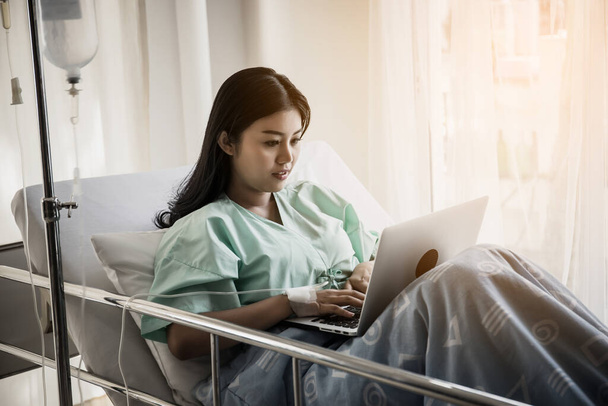 Sick woman works with laptop in hospital. - Zdjęcie, obraz