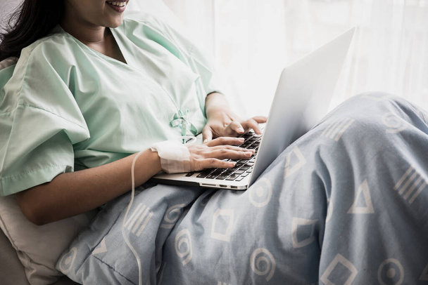 Zieke vrouw werkt met laptop in ziekenhuis. - Foto, afbeelding