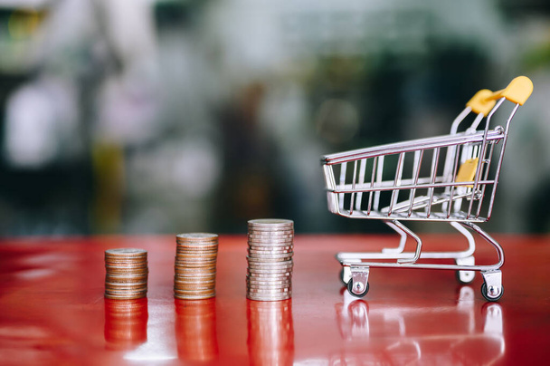 shopping cart with step of coins stacks, money, shopping saving and investment or family planning concept. - Photo, Image
