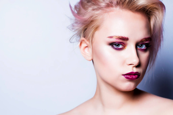Fashion model with bright makeup looks in the frame on a gray background. Photo with place for text. - Фото, изображение
