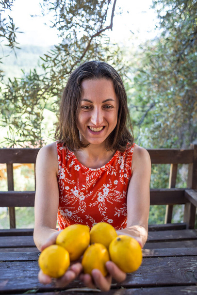 Woman holds freshly picked lemons in her hands, Harvest of citrus fruits, The girl holds out a lemon in a palm. - Photo, Image