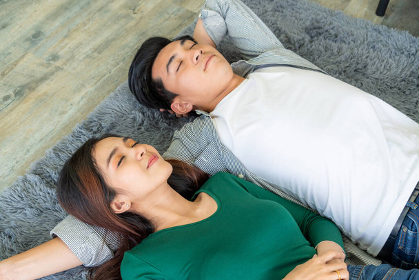 Heureux couple asiatique couché ensemble sur le tapis au sol du salon. relation d'amour et concept de style de vie. - Photo, image