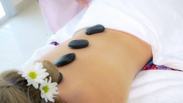 Жінка отримує масаж гарячим каменем від професійного косметолога в спа-салоні. Розкішне оздоровлення, полегшення стресу спини та концепція омолодження
. - Фото, зображення