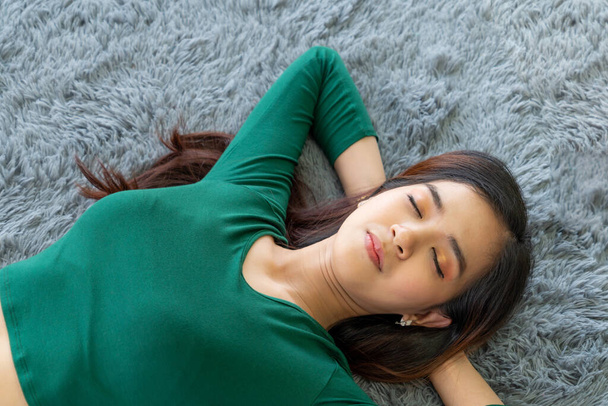 Счастливая азиатская пара, лежащая вместе на ковре на полу в гостиной. Концепция любовных отношений и образа жизни. - Фото, изображение
