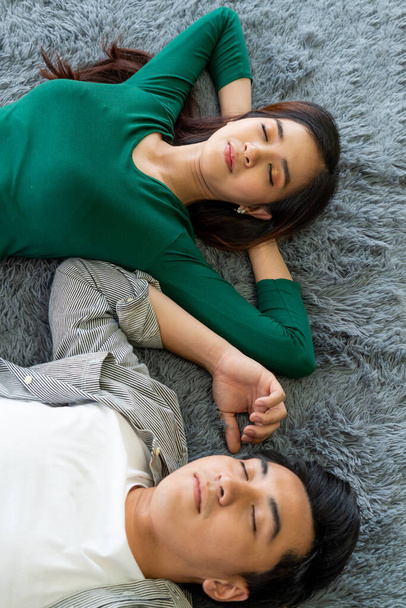 Щаслива азіатська пара лежала разом на килимі на підлозі вітальні. Любовні взаємини і спосіб життя. - Фото, зображення