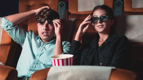 Hombre y mujer en el cine viendo una película con gafas 3D. con interés mirando la pantalla, emocionantes y comiendo palomitas de maíz - Foto, Imagen