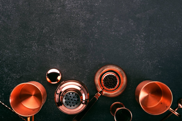 Copper bar tools and accessories for making cocktail. Shaker, jigger, strainer, spoon. Alcohol drinks and beverages preparation concept. Black background, top view, copy space - Photo, Image