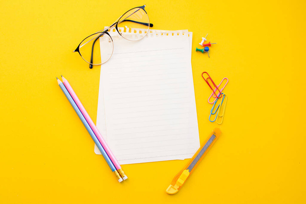empty paper of notebook eyeglasses and pencil on color background. - Foto, Imagem