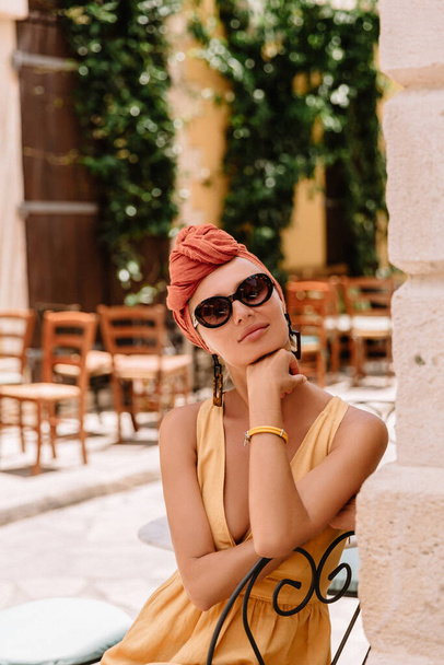 Pretty young female tourist posing in front of beautiful door in the centre of old mediterranean town, her hairstyle enhanced by turban - 写真・画像