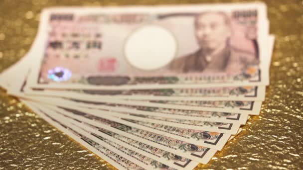 Close-up rack βίντεο εστίαση σε 100.000 γιεν σε μετρητά σε ένα χρυσό χαρτί. - Πλάνα, βίντεο