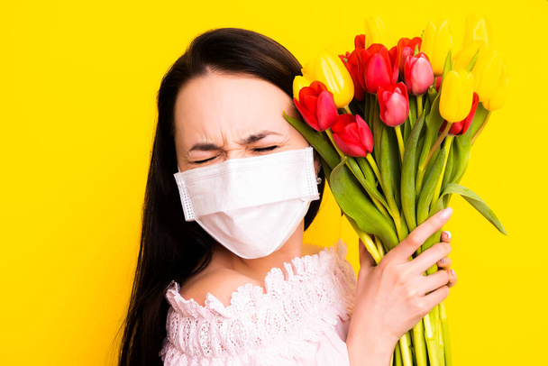 Allergy to indoor and outdoor flowers. Allergy. Woman with a bouquet of flowers in a mask. - Фото, изображение
