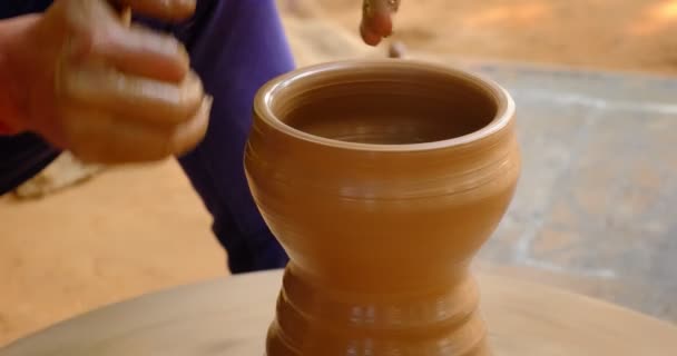 Garncarstwo - wykwalifikowane mokre ręce garncarza kształtującego glinę na kole garncarskim. Trawka, rzucanie wazą. Produkcja tradycyjnego rzemiosła indyjskiej miski, słoik, dzbanek, dzbanek. Shilpagram, Udaipur, Rajasthan, Indie - Materiał filmowy, wideo