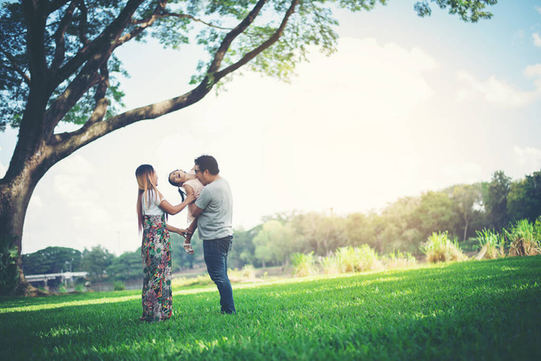Familia feliz en el parque, Padre y Madre jugando con su hija, relajarse tiempo en familia
 - Foto, Imagen