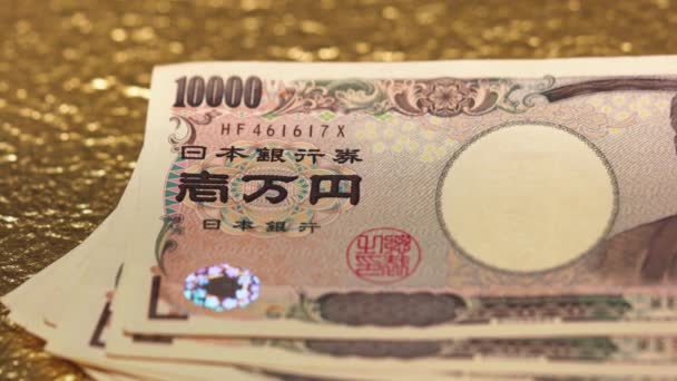 Közelkép diavideó 100.000 jenről készpénzben egy aranypapíron.. - Felvétel, videó
