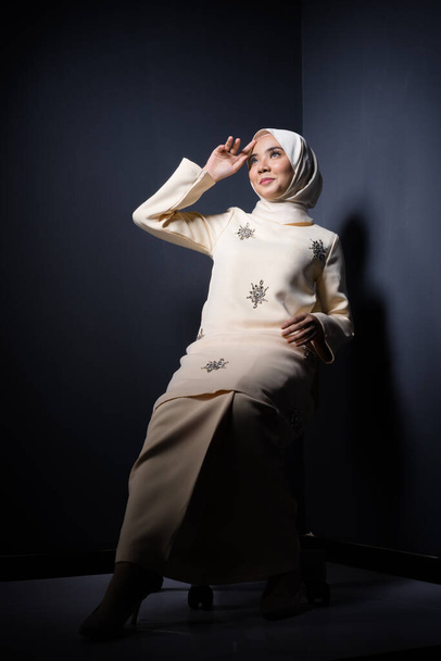 Hijab beauty and fashion editorial concept. A beautiful Muslim model in modern kurung and hijab in various editorial poses for a studio photoshoot. Full length portrait. - Фото, зображення