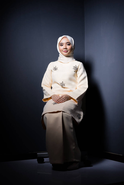 Hijab Schönheit und Mode Redaktionskonzept. Ein schönes muslimisches Model in modernem Kurung und Hijab in verschiedenen redaktionellen Posen für ein Fotoshooting im Studio. Ganzes Porträt. - Foto, Bild