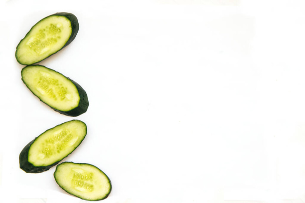  Cucumbers cut into circles on a white background. Green vegetables. Young and fresh cucumber. - Foto, afbeelding