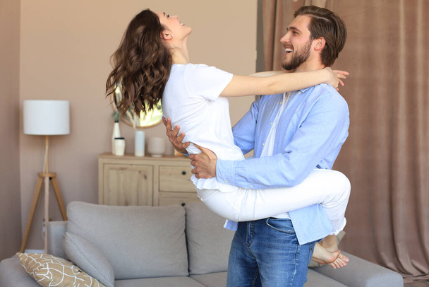 Young joyful couple having fun swirling in living room together, happy couple dancing swaying at home - Fotografie, Obrázek
