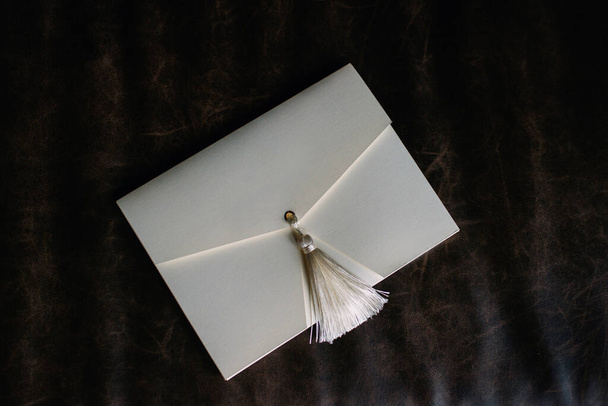 Handgemaakte cadeau envelop op een bruine lederen ondergrond. verpakking. Huwelijksuitnodigingskaarten. Plat gelegd. Kopieerruimte. - Foto, afbeelding