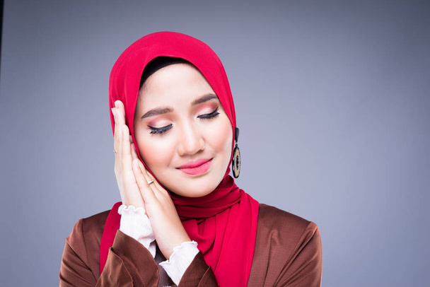 Imagen de una hermosa modelo musulmana con un vestido tradicional musulmán asiático y un hiyab aislado sobre fondo gris. Eidul fitri moda y estilo de vida concepto de retrato
 - Foto, Imagen