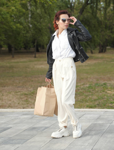 Élégante belle femme tient sac en papier artisanal à l'extérieur
. - Photo, image