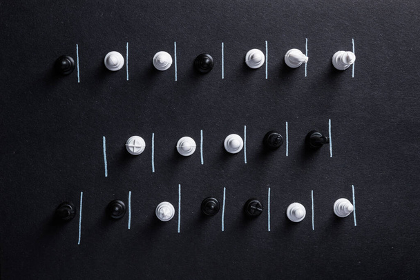 Chess pieces on a dark background with constraint lines. Concept of social distancing during the coronavirus pandemic time. Distance in queues. Top view. each in his place. - Fotografie, Obrázek
