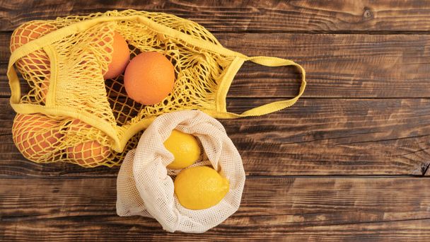 Düz meyve ve sebze portakalları, ekolojik olarak yeniden kullanılabilir pamuk torbalarında limonlar, ahşap bir masa üzerinde biyolojik olarak çözünebilir, fotokopi alanı olan arka plan. Sosyal çevre sorumluluğu kavramı - Fotoğraf, Görsel