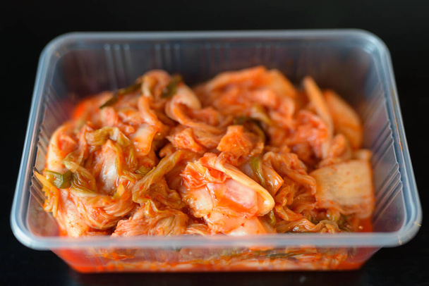 coreano cibo kimchi servito in contenitore di plastica orizzontale girato su sfondo nero
 - Foto, immagini