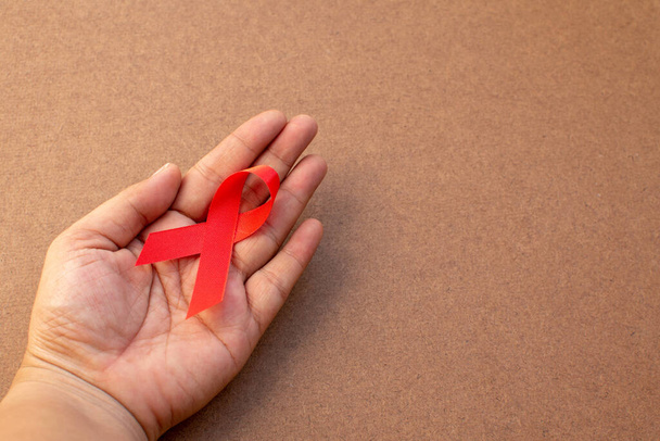 Red ribbon on hand with World Aids day concept.  - Foto, imagen