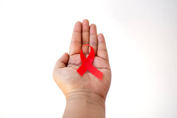 Red ribbon on hand with World Aids day concept.  - Photo, Image