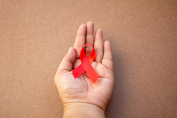 Fita vermelha na mão com conceito Dia Mundial da Aids
.  - Foto, Imagem