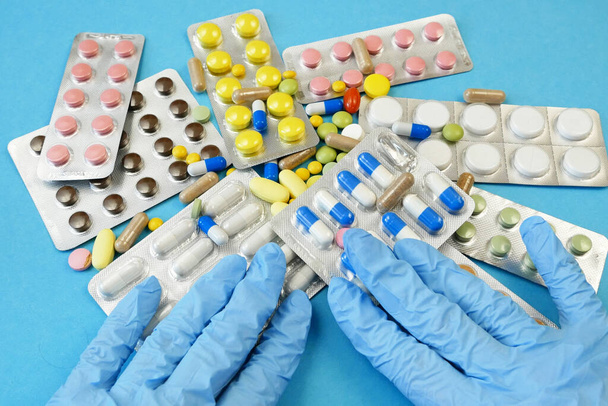 handen in handschoenen te verplaatsen pillen in blaren, drugs en tabletten, alternatieve geneeskunde concept - Foto, afbeelding