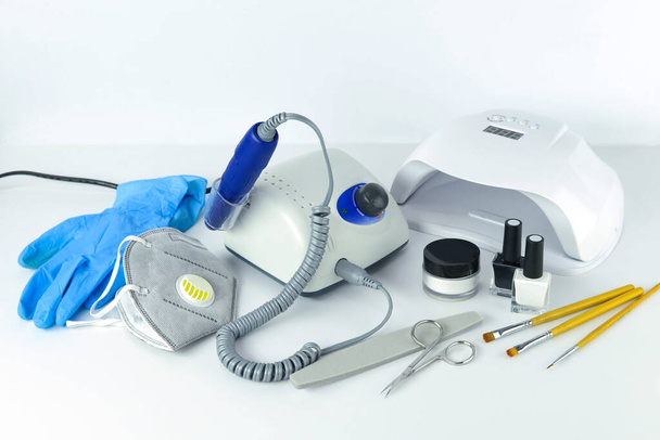 Manicure tools and equipment. A medical mask and rubber gloves lie next to the manicure machine. - Foto, Bild