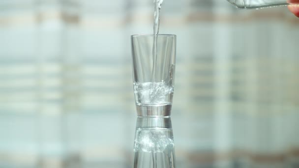 Prázdné sklo stojí na skleněném stole a nalévá čistou vodu do sklenice - Záběry, video