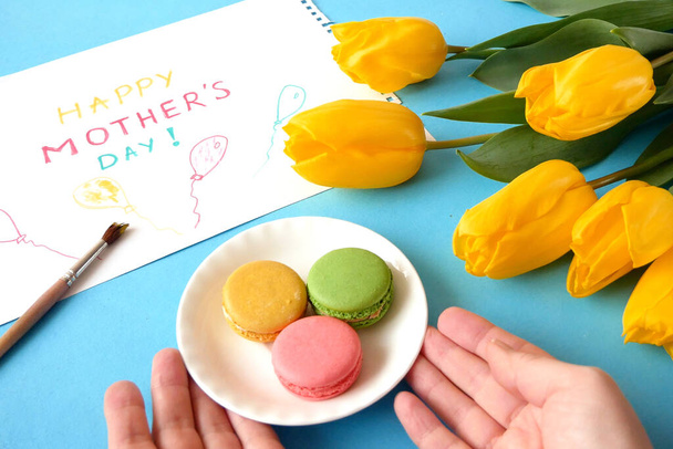 kaunis keltainen tulppaanit kimppu, ruusut, ranskalainen makaroni ja onnittelukortti, onnellinen äitienpäivä, näkymä alkuun, äitienpäivä aamiainen - Valokuva, kuva