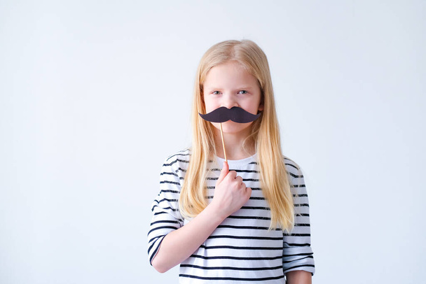 funny child blonde girl with mustache on grey background. Copyspace. Happy father day. - 写真・画像