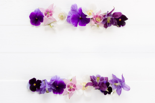 Квіти плоский дизайн. Квіткова рама фіолетова, фіолетова, рожеві білі квіти. Шаблон з копіюванням простору на білій дерев'яній дошці. Viola, Aquilegia, Anemone flowers - Фото, зображення