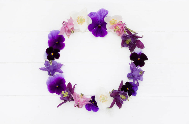 Flowers flat design. Floral round  frame, flowers wreath with   violet , purple, pink white  flowers. Template with copy space on white wooden board. Viola , Aquilegia,  Anemone flowers. - Zdjęcie, obraz