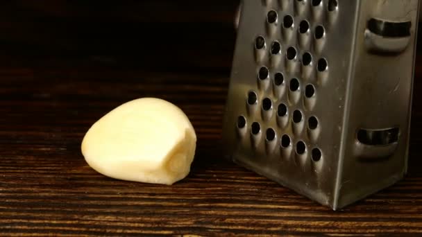 Chef mãos esfregando cravo de alho em ralador de metal pequeno na placa da cozinha. Close-up
. - Filmagem, Vídeo