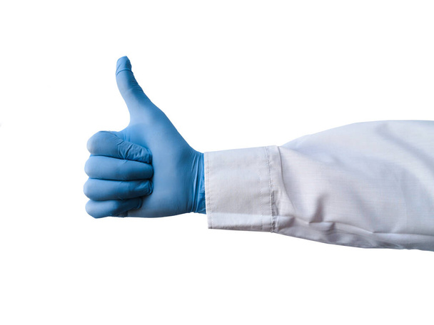 Dłoń pracownika medycznego pokazuje kciuk w górę na białym, odizolowanym tle. Ręczne gesty. Zbliżenie dłoni pokazuje kciuk w górę. - Zdjęcie, obraz