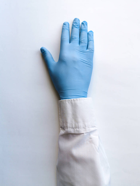 La main d'un travailleur médical dans un gant bleu repose sur une table blanche
 - Photo, image