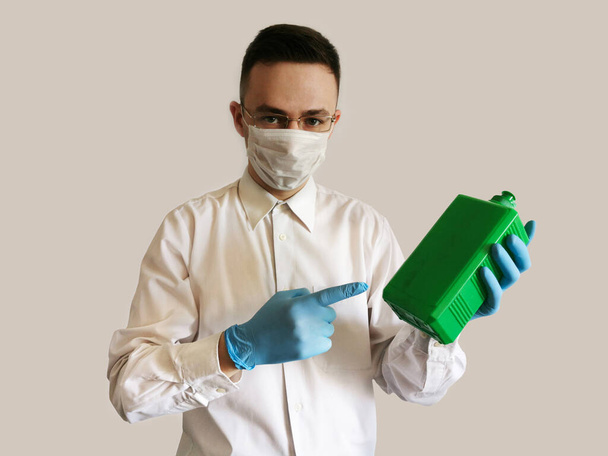 Mediziner in Handschuhen und Brille zeigt auf eine antiseptische Flasche - Foto, Bild