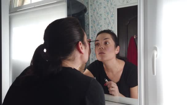 Schöne brünette Frau beim Make-up vor dem Spiegel im Badezimmer - Filmmaterial, Video