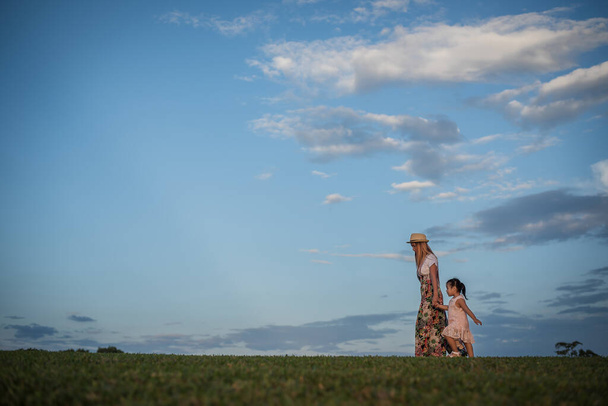 Fiatal anya és kislánya sétálnak a parkban - Fotó, kép