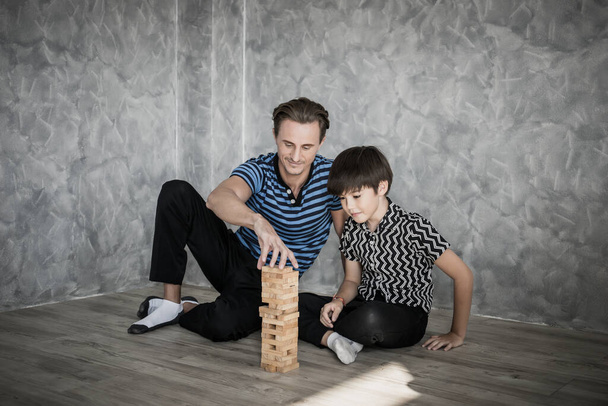 Father and son playing Jenga  in house. Happy family concept. - Фото, зображення