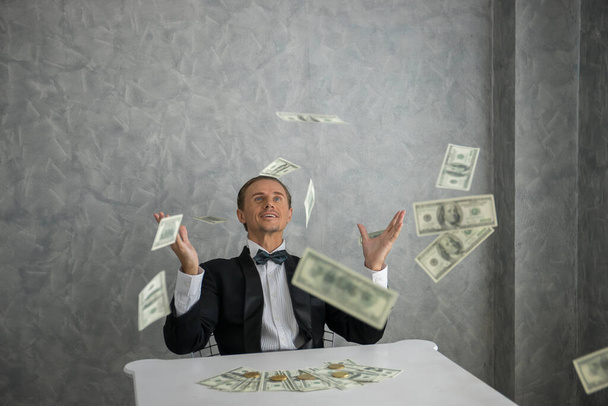 Бізнесмен дивиться на доларові купюри, що падають навколо нього
 - Фото, зображення