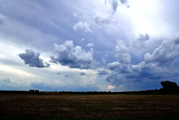 Lapos barna gazdaság mezők viharos felhő borította kék ég elején a gazdálkodási szezon több sor viharfelhők.  - Fotó, kép