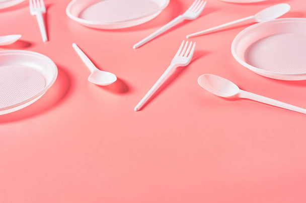 Disposable plastic utensils scattered on pink background. Concept of save environment, ecology, recreation on picnic, party and other events. Copy space - Photo, Image