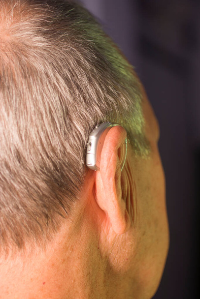 biały biały starzec noszący nowoczesny cyfrowy aparat słuchowy w uchu z siwymi włosami. - Zdjęcie, obraz