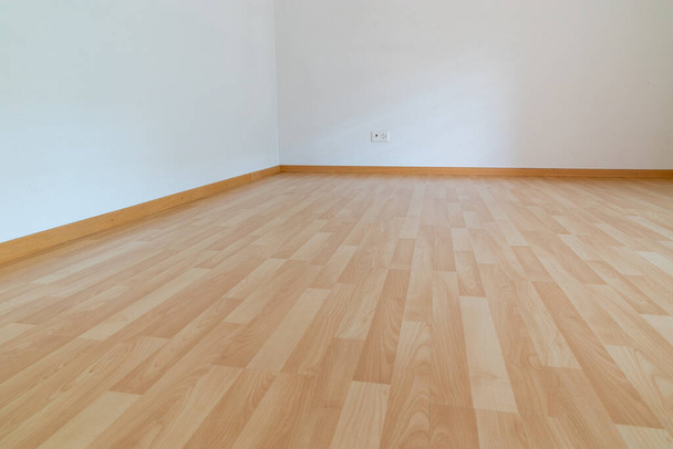 Uma visão horizontal de baixo ângulo de novo piso em parquet de madeira em uma luz brilhante e sala de apartamento branco
 - Foto, Imagem